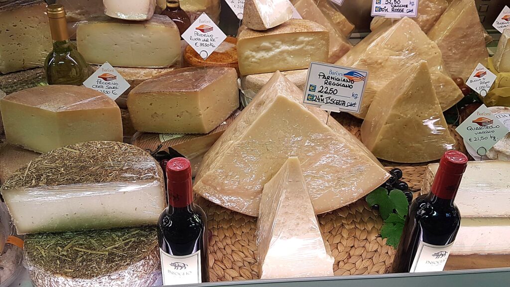 Italian cheese counter with pecorino and Parmigiano Reggiano wheels, hand-written price tags